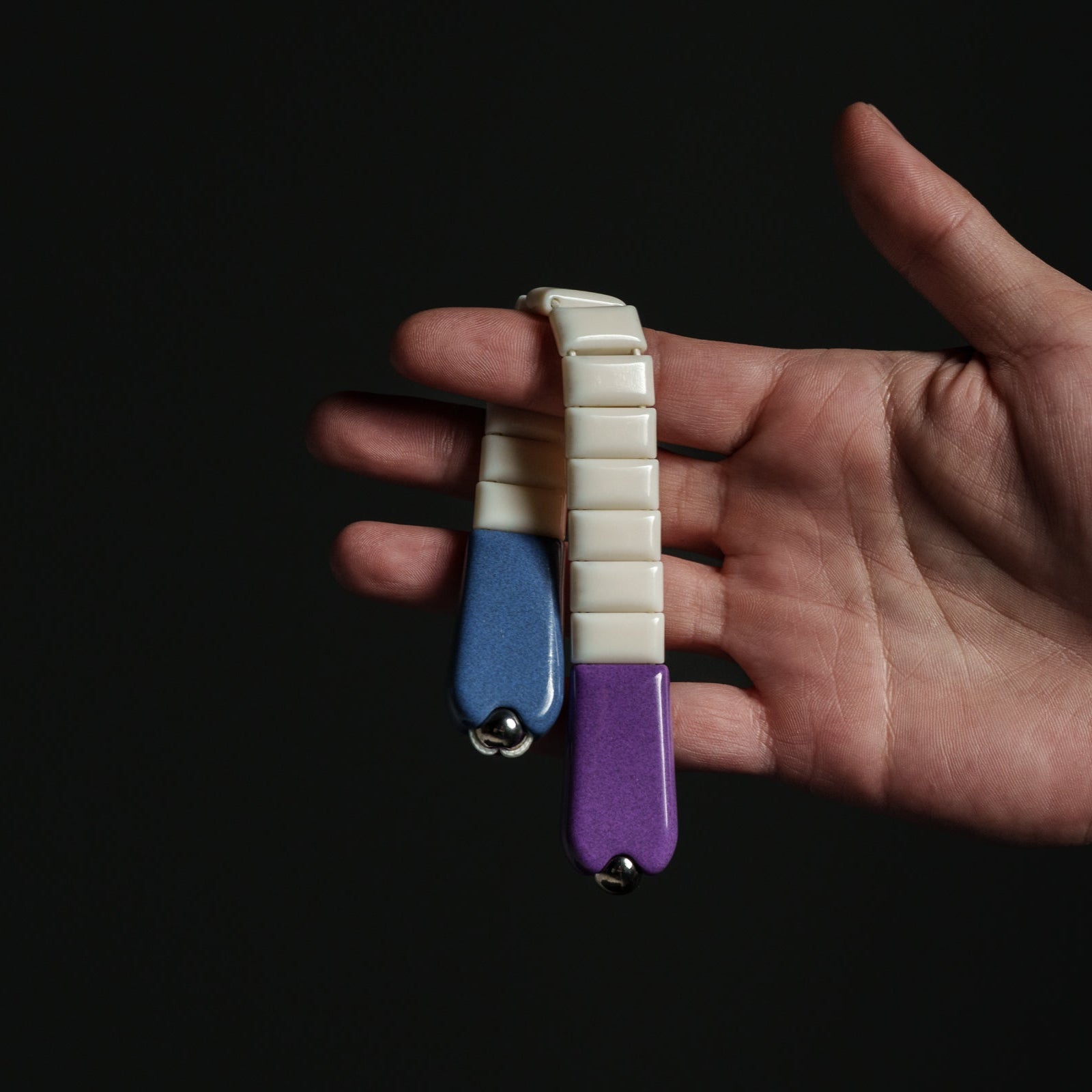 Hand holding a small, multicolored chetki against a dark background