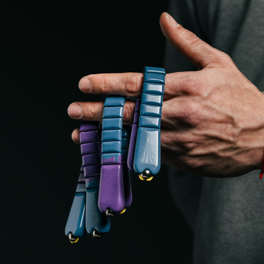 Person holding three colorful chetki against a dark background