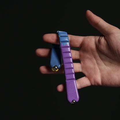 Hand holding a purple and blue chetki against a black background