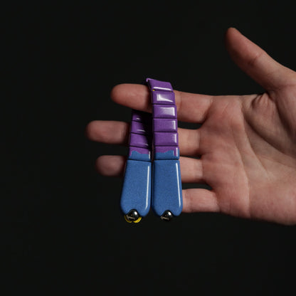 Hand holding a blue and purple chetki against a black background
